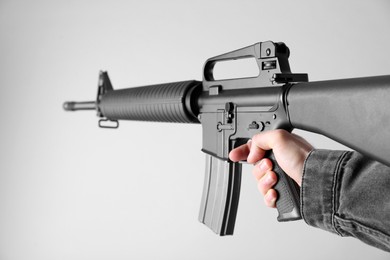 Assault gun. Man aiming rifle on light background, closeup