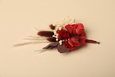 Photo of Stylish red boutonniere on beige background. Beautiful accessory