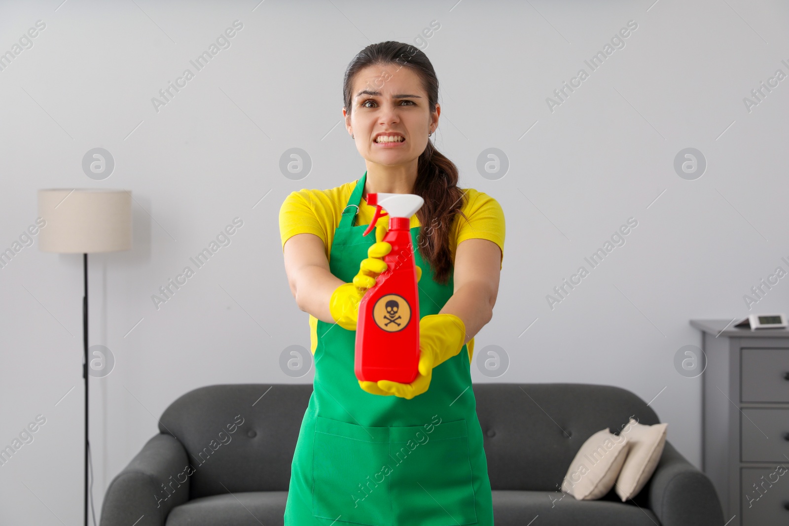 Photo of Woman showing bottle of toxic household chemical with warning sign indoors