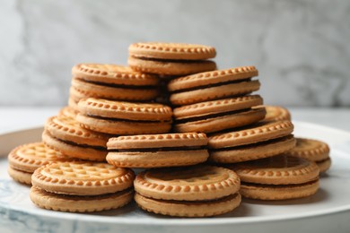 Photo of Tasty sandwich cookies with cream on white marble tray, closeup