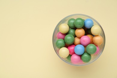 Photo of Bowl with many bright gumballs on beige background, top view. Space for text