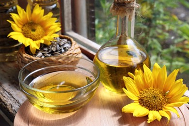 Photo of Organic sunflower oil and flowers on window sill indoors, closeup