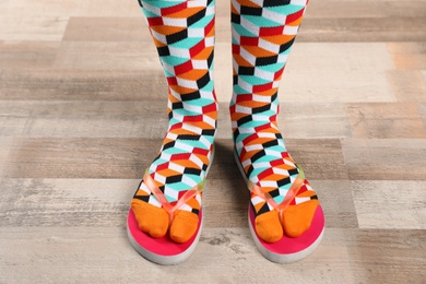 Photo of Woman wearing bright socks with flip-flops standing on floor
