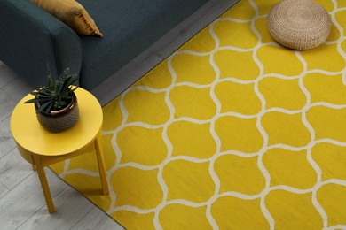 Photo of Yellow carpet with geometric pattern on wooden floor in living room, above view