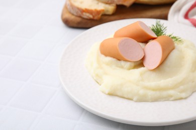 Delicious boiled sausages and mashed potato on white tiled table, closeup