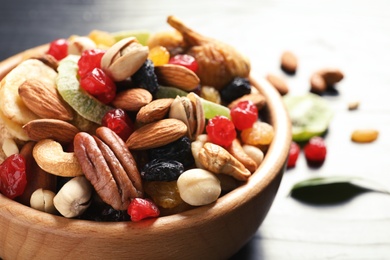 Photo of Bowl with different dried fruits and nuts on table, closeup