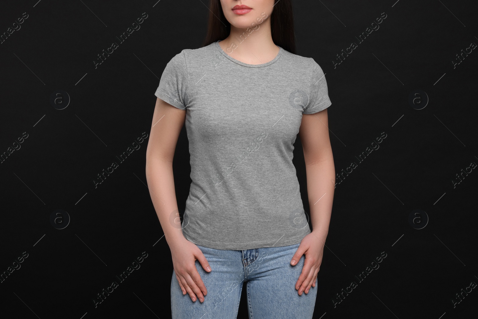 Photo of Woman wearing grey t-shirt on black background, closeup