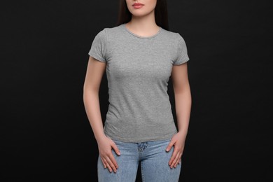 Photo of Woman wearing grey t-shirt on black background, closeup