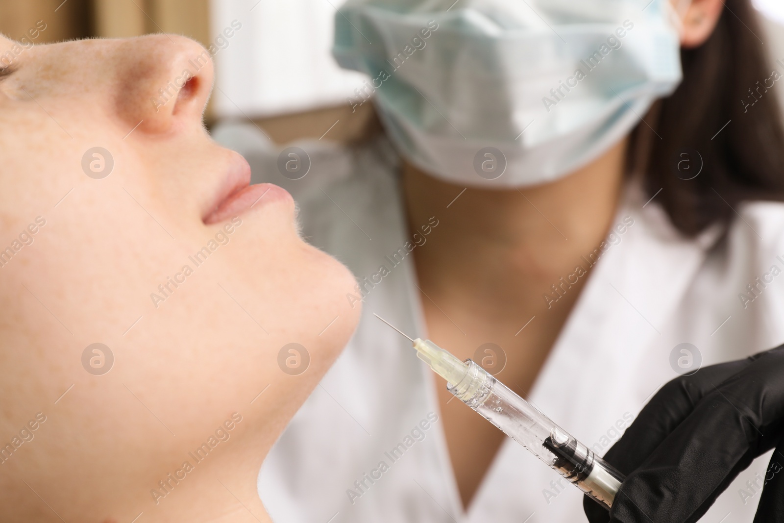 Photo of Cosmetologist giving facial injection to patient in clinic, closeup. Cosmetic surgery