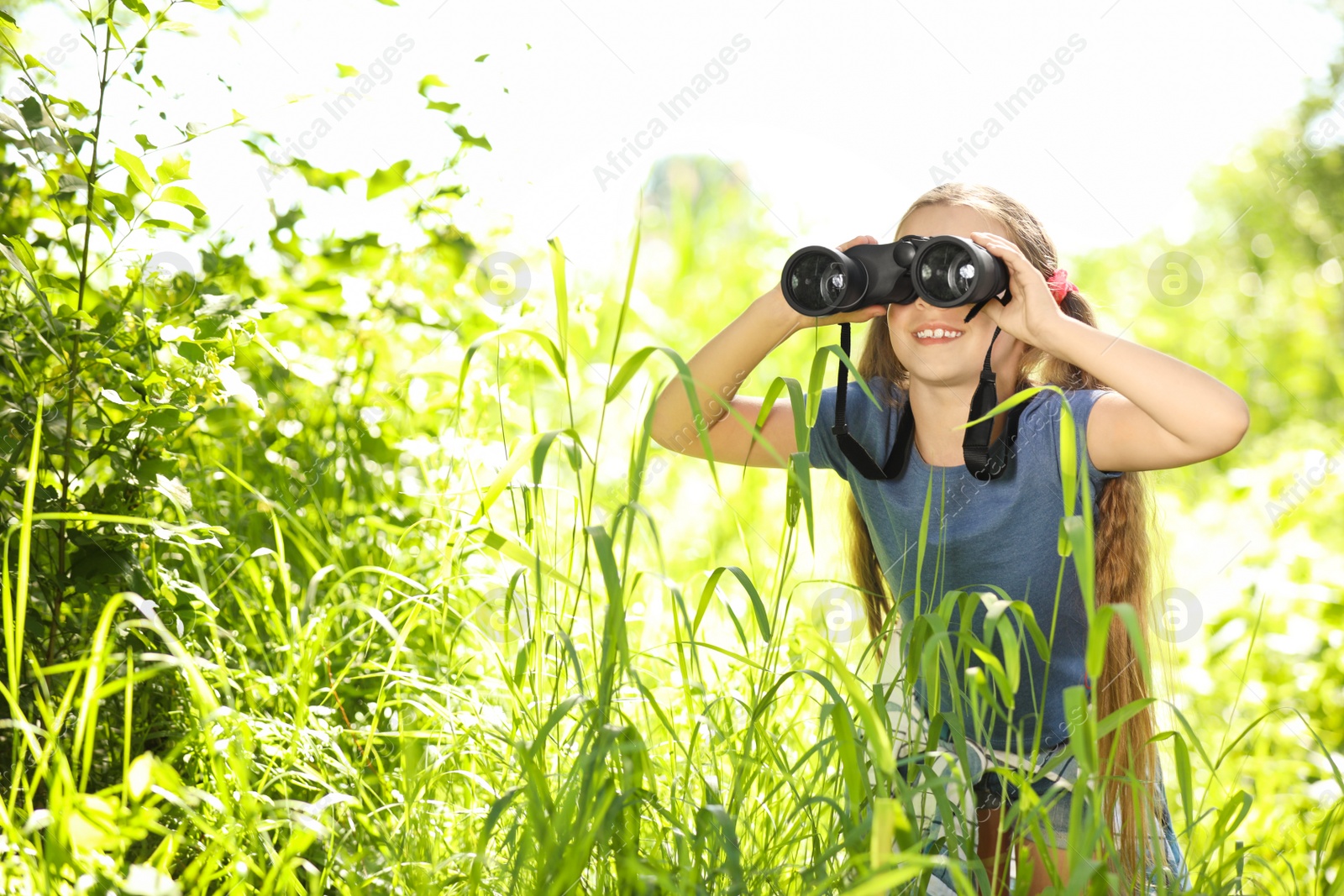 Photo of Little girl with binoculars outdoors. Summer camp