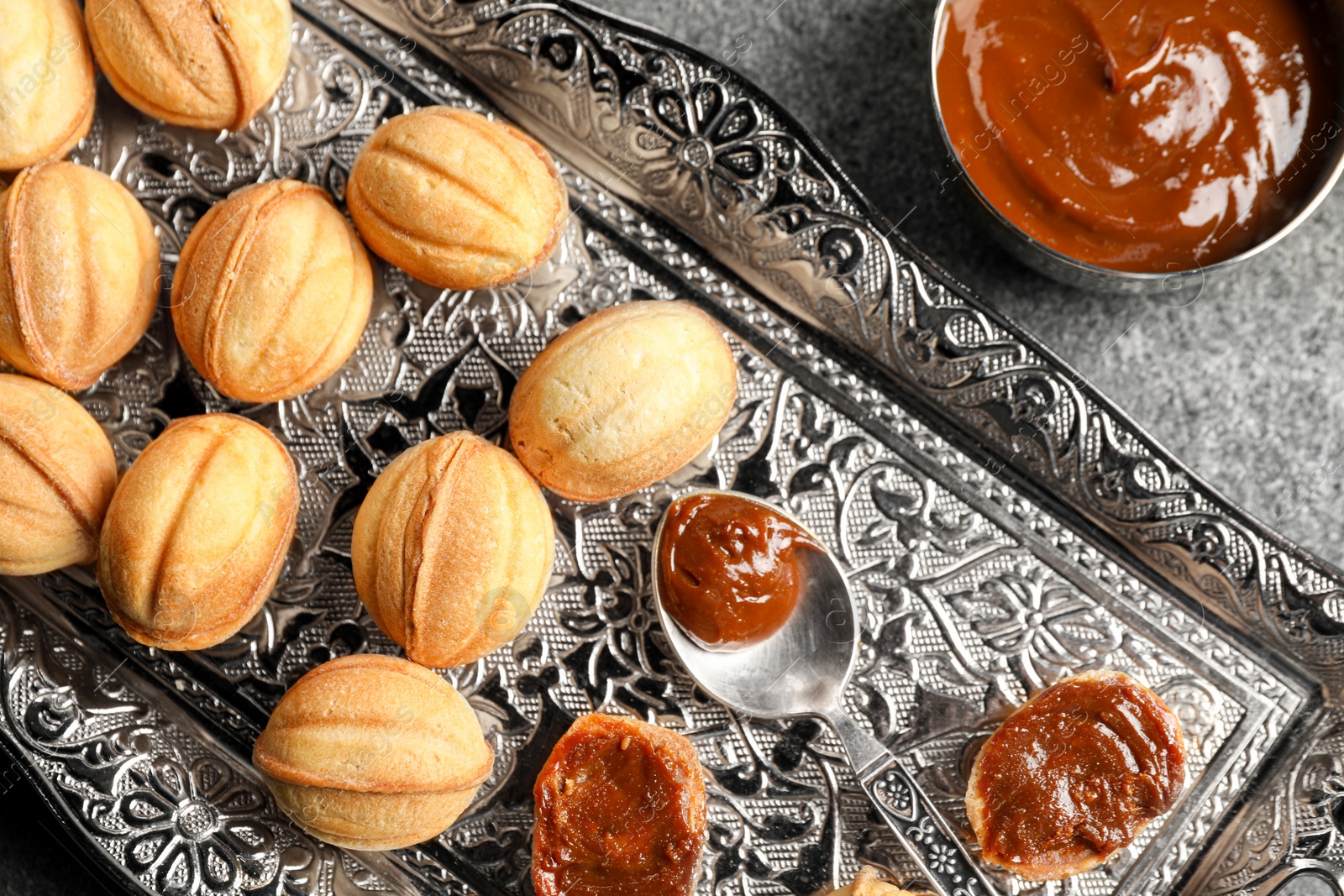 Photo of Homemade walnut shaped cookies with boiled condensed milk on grey table, flat lay