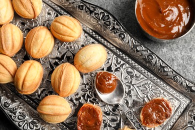 Photo of Homemade walnut shaped cookies with boiled condensed milk on grey table, flat lay