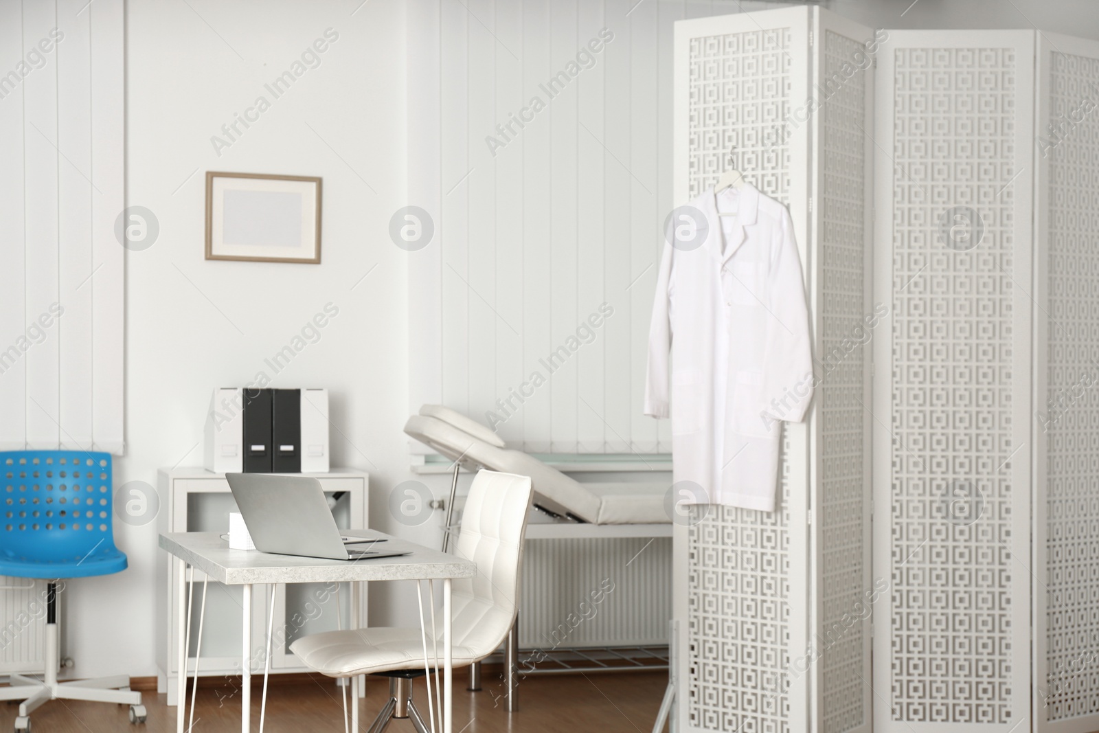 Photo of Doctor's office interior with desk, examination couch and folding screen