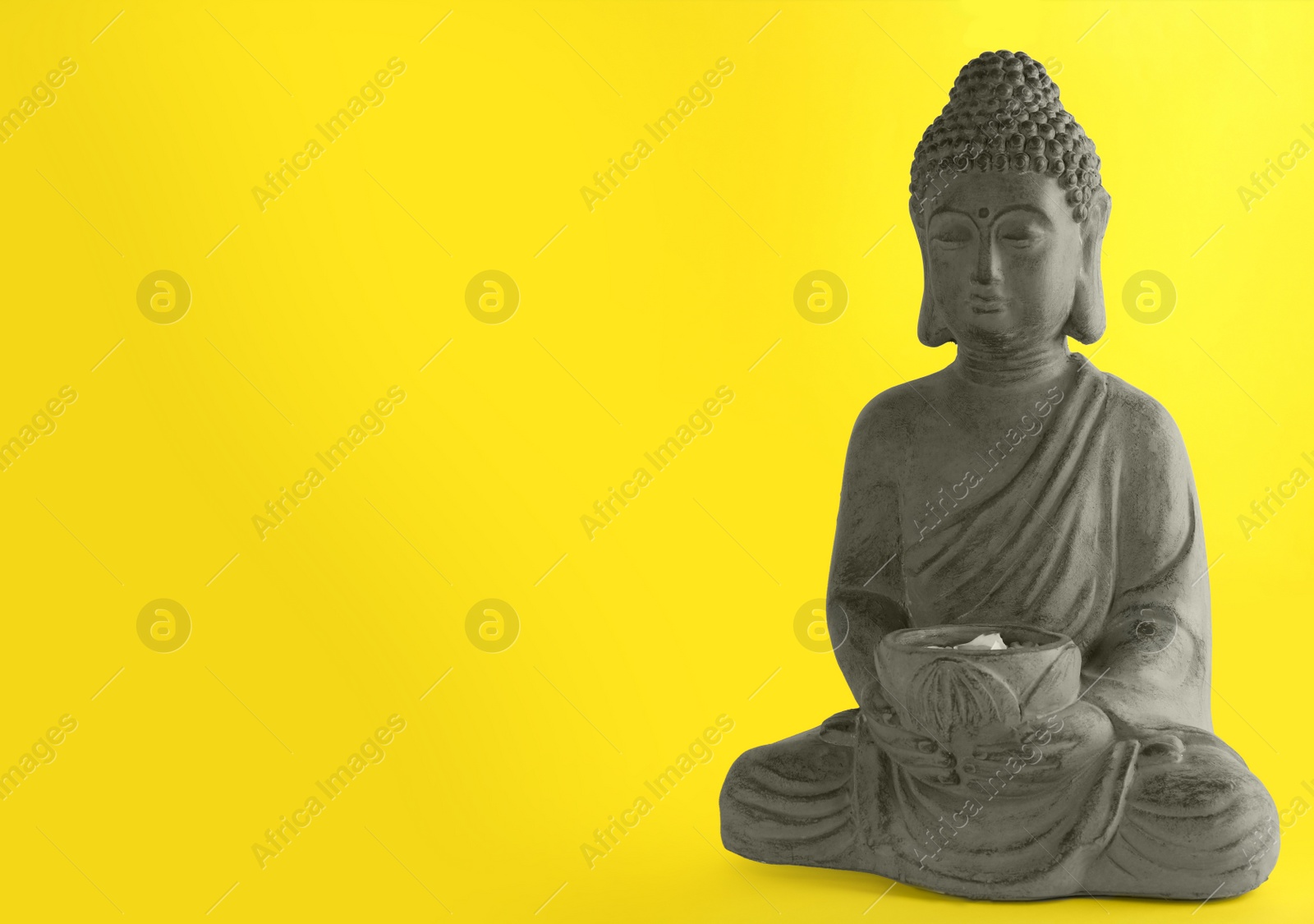 Photo of Beautiful stone Buddha sculpture on yellow background. Space for text