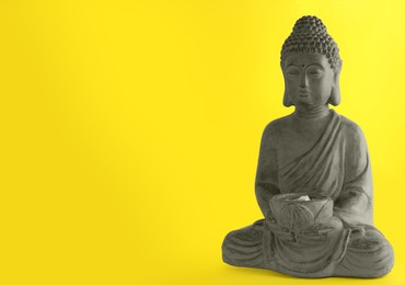Beautiful stone Buddha sculpture on yellow background. Space for text
