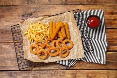 Tasty ketchup with snacks on wooden table, top view
