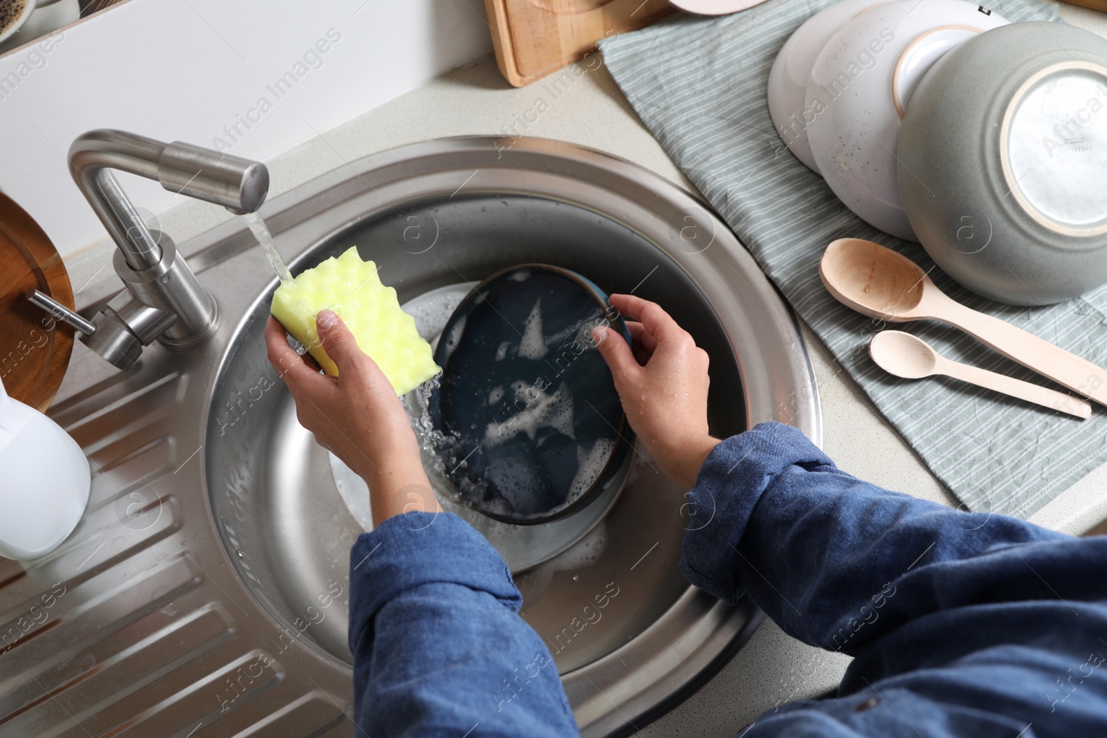 Photo of Woman washing plate in kitchen sink, above view