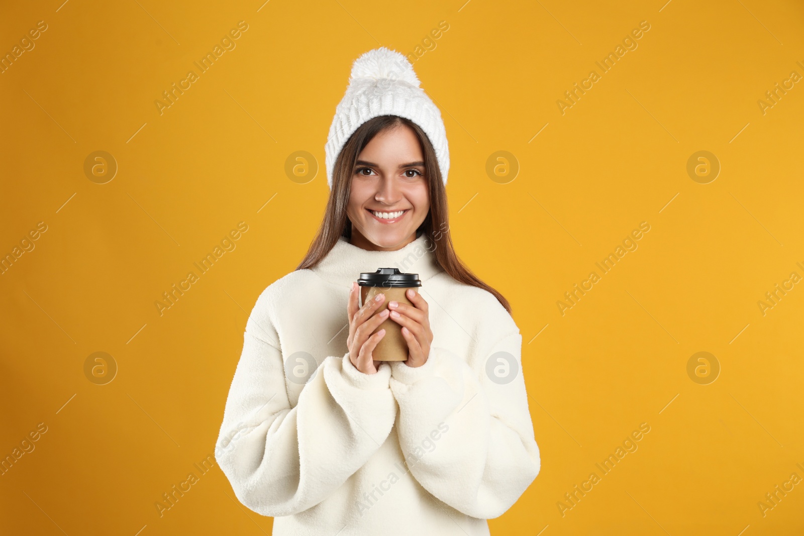 Photo of Happy beautiful woman with paper cup of mulled wine on yellow background