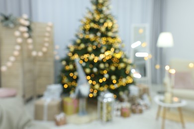 Blurred view of Christmas tree, gift boxes and festive decor in room. Interior design