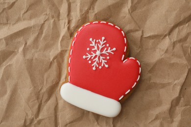 Photo of Christmas mitten shaped gingerbread cookie on crumpled parchment, top view