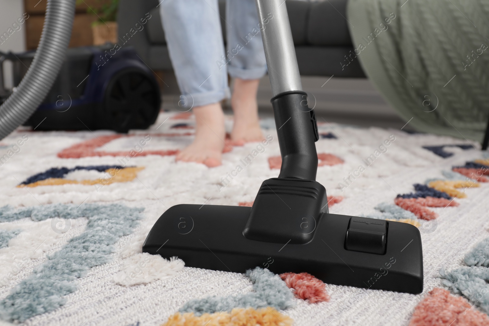 Photo of Woman cleaning carpet with vacuum cleaner at home, closeup