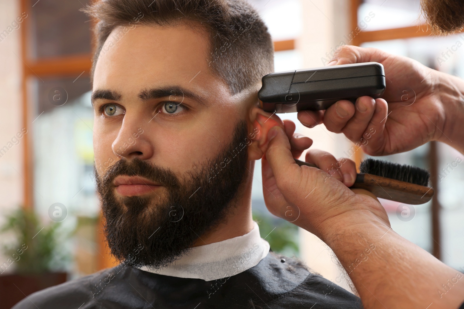 Photo of Professional hairdresser working with client in barbershop, closeup