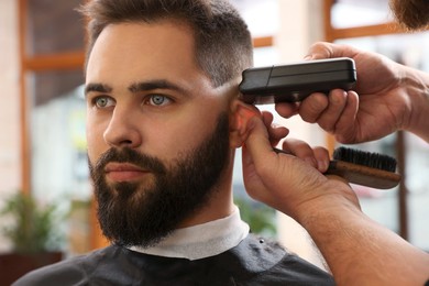 Photo of Professional hairdresser working with client in barbershop, closeup