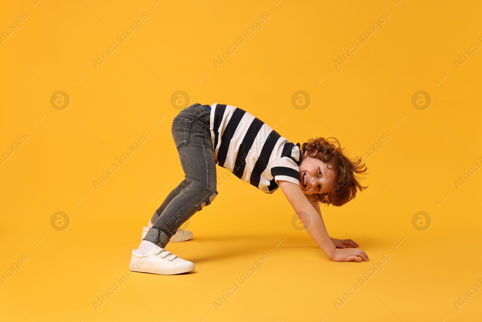 Photo of Happy little boy dancing on yellow background