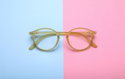 Photo of Glasses with corrective lenses on color background, top view