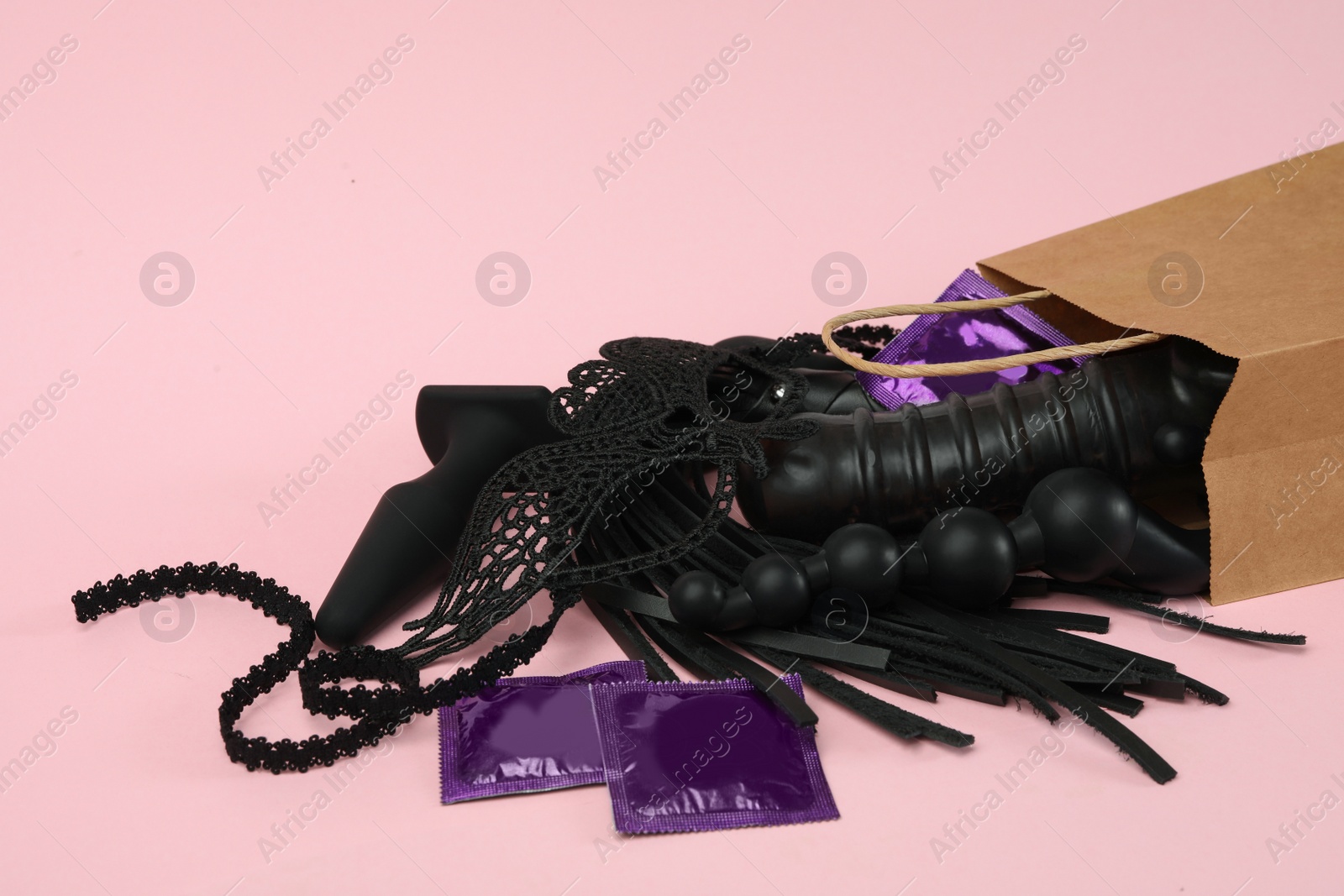 Photo of Shopping bag and different sex toys on pink background