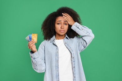 Photo of Confused woman with credit cards on green background. Debt problem