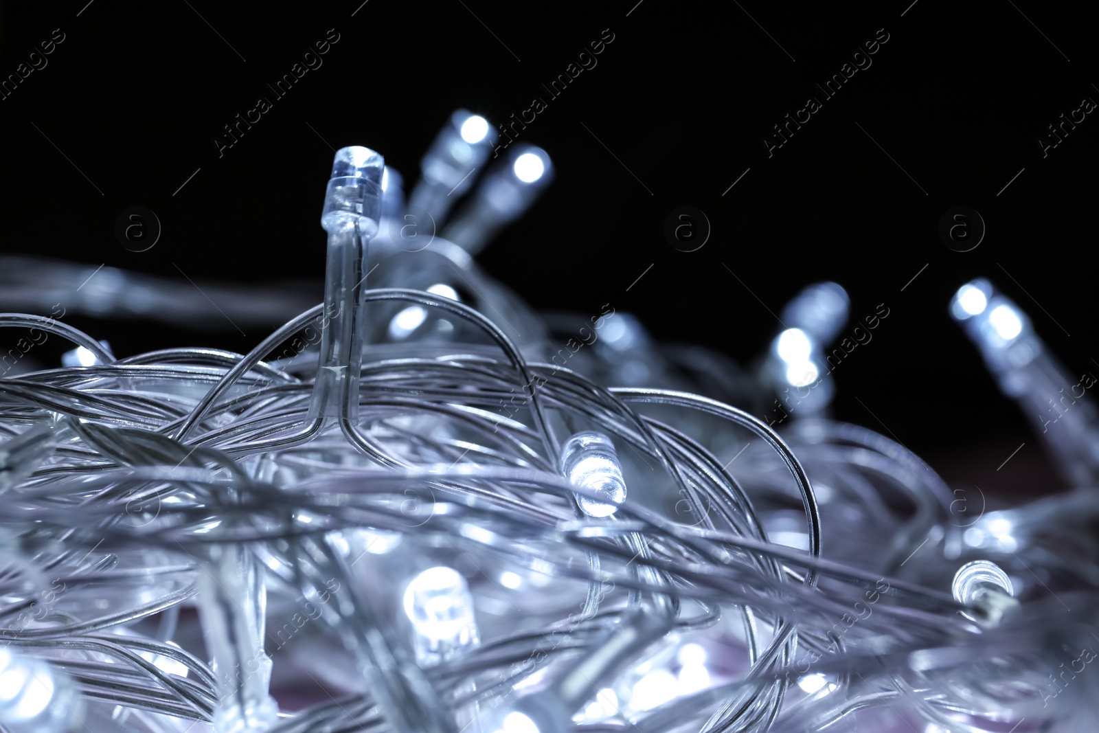 Photo of Glowing Christmas lights on dark background, closeup