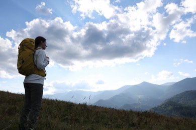 Photo of Tourist with backpack enjoying mountain landscape. Space for text
