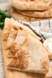 Photo of Cut pita bread on white wooden table, closeup