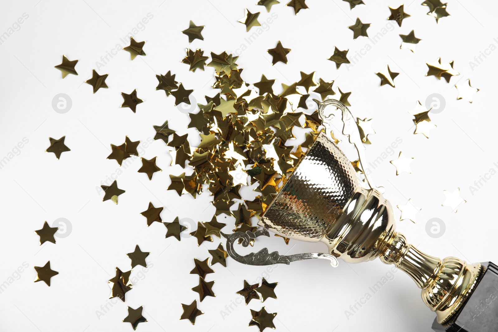 Photo of Gold trophy cup and confetti on white background, top view