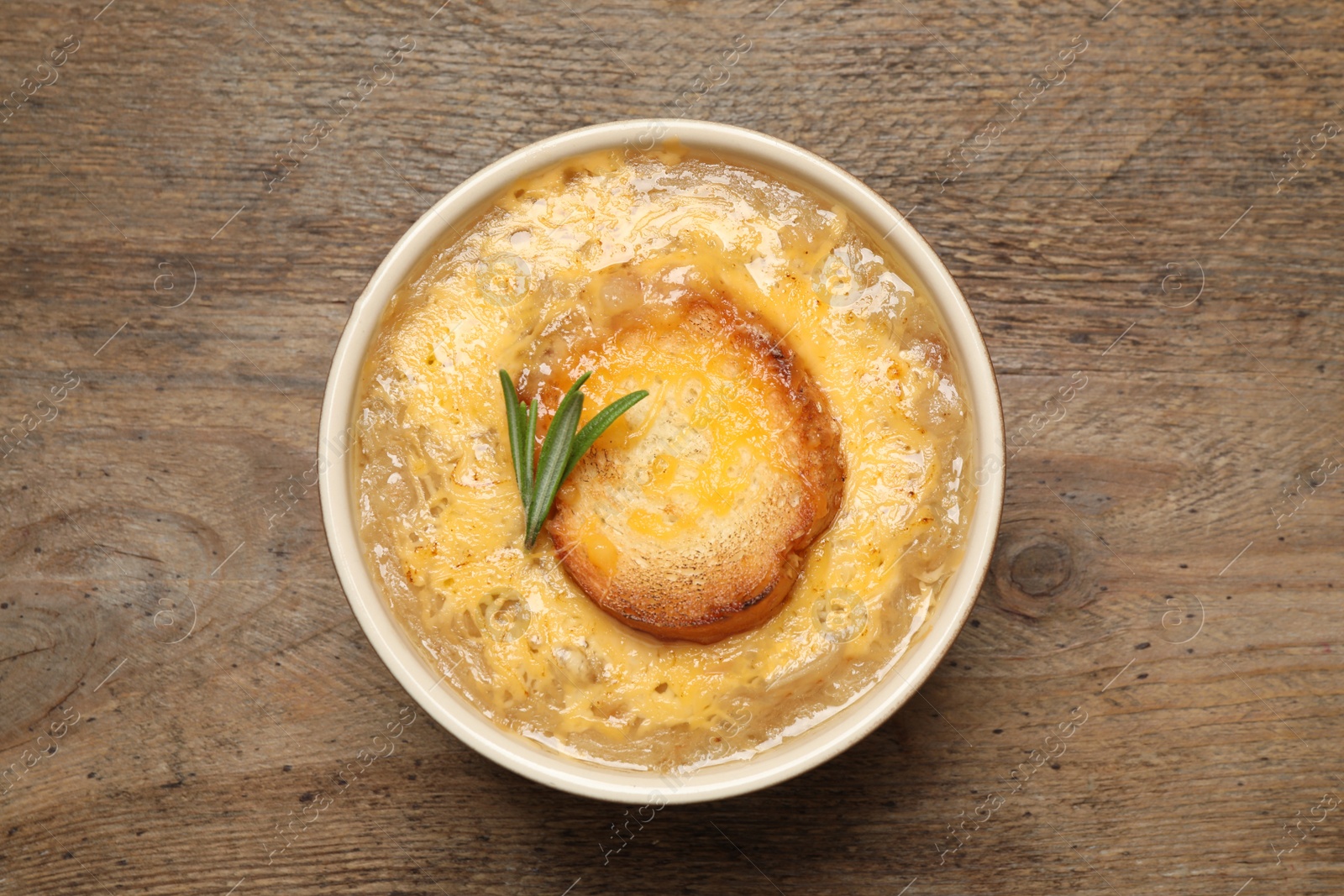 Photo of Tasty homemade french onion soup on wooden table, top view