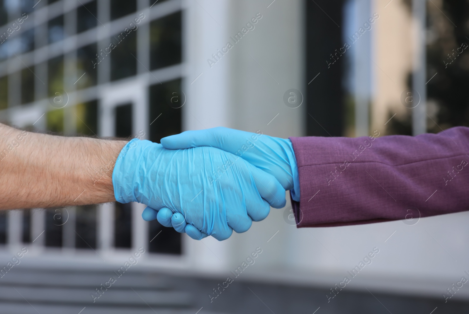 Photo of Man and woman in protective gloves shaking hands to say hello outdoors, closeup