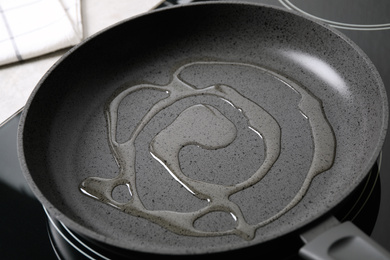 Photo of Frying pan with cooking oil on induction stove