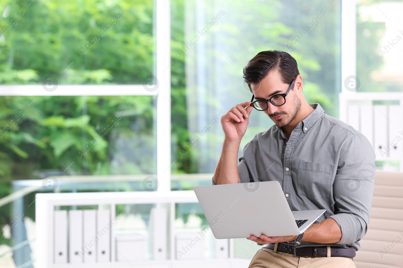 Photo of Handsome young man working with laptop indoors. Space for text