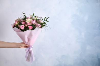 Woman with bouquet of beautiful roses on light blue background, closeup. Space for text