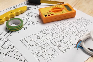 Photo of Wiring diagrams, wires and digital multimeter on wooden table, closeup