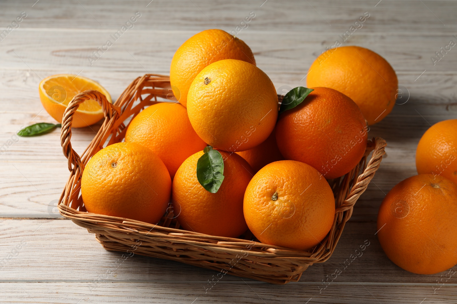 Photo of Many ripe oranges and green leaves on wooden table