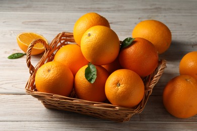 Many ripe oranges and green leaves on wooden table