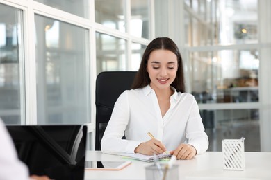 Photo of Happy woman taking notes at white desk in open plan office, space for text