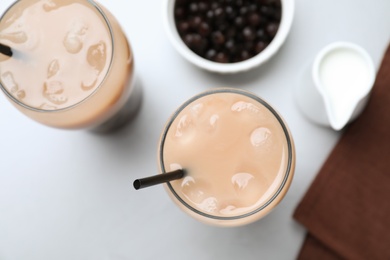 Bubble milk tea and bowl with tapioca balls on light grey table, flat lay