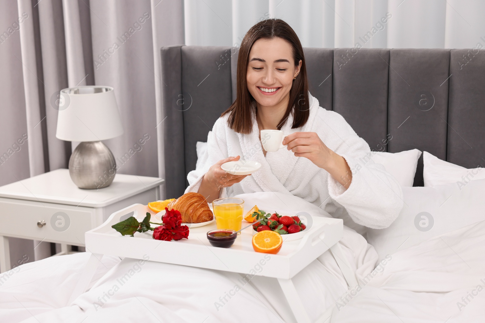 Photo of Smiling woman having breakfast in bed at home