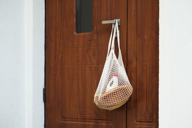 Photo of Helping neighbours. Net bag of products hanging on door outdoors