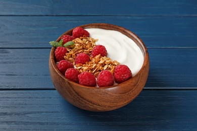 Photo of Bowl of tasty yogurt with raspberries and muesli served on blue wooden table