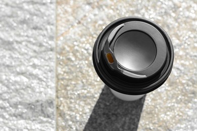 Takeaway coffee cup on stone surface outdoors, top view. Space for text