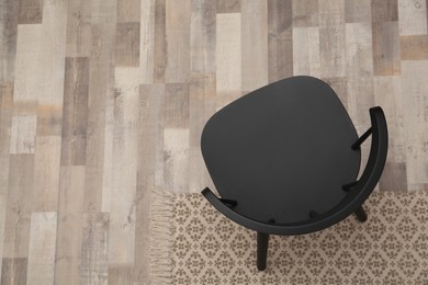 Photo of Stylish comfortable black chair on floor, top view. Space for text